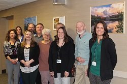 Patient Family Engagement Committee members pose in front of donated photos