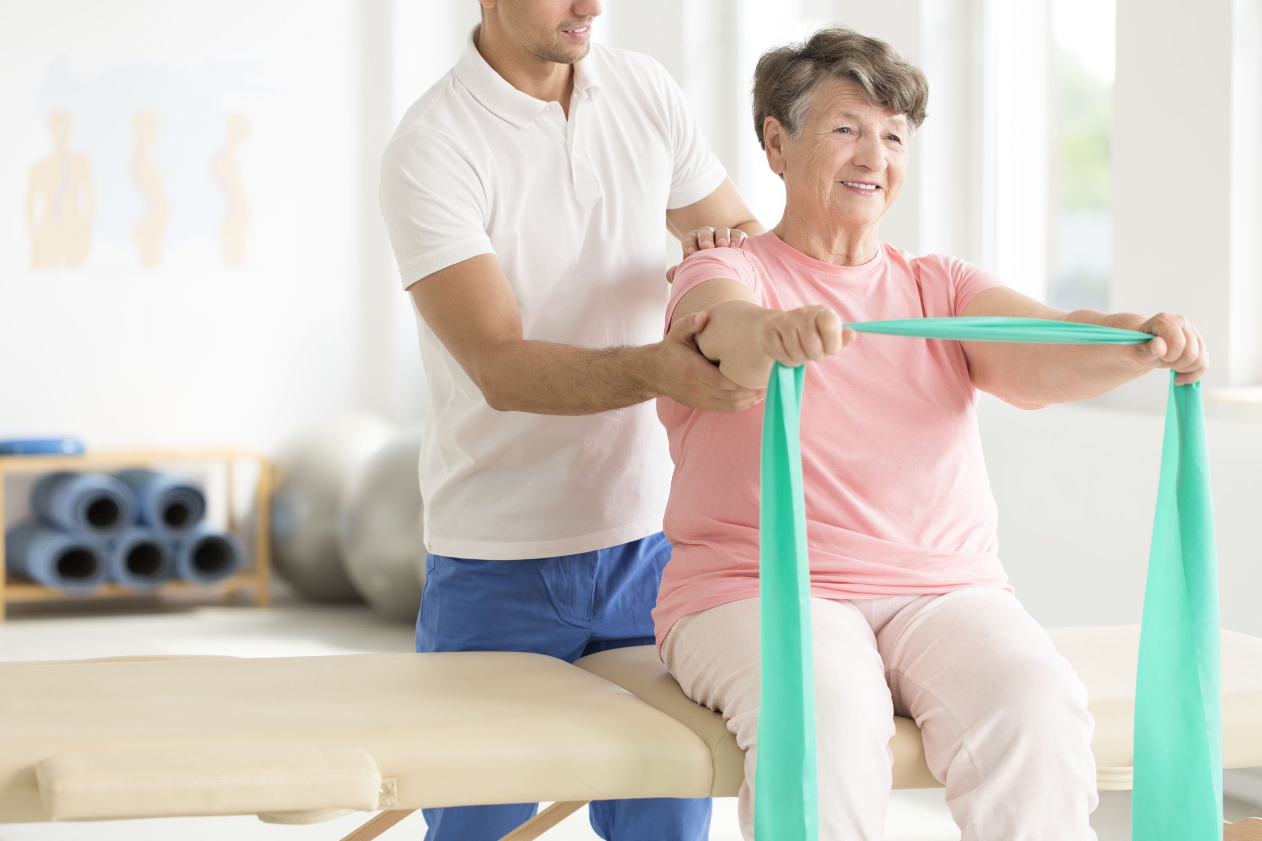 older woman working out with band and physical therapist
